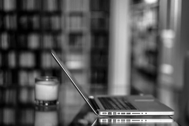 Чёрно-белая фотография MacBook на библиотечном столе